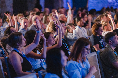 Audience clapping and raising hands during a UXDX session