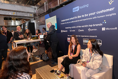 Attendees chatting at a partner booth at UXDX