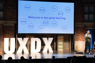 Speaker on stage beside the giant UXDX letters