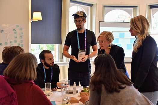 Group working at a table with instructors standing over them helping